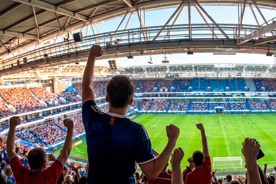 Aficionados en un estadio celebrando un partido con números de lotería inspirados en el futbol