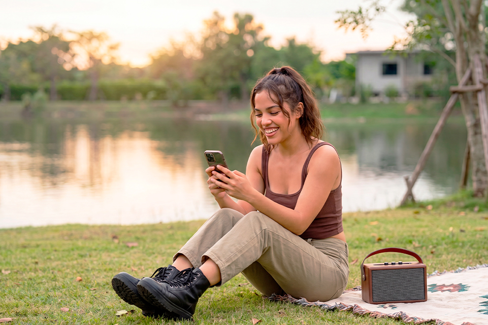 Mujer sonriente usando su celular al aire libre para celebrar el Día Internacional de la Amistad.