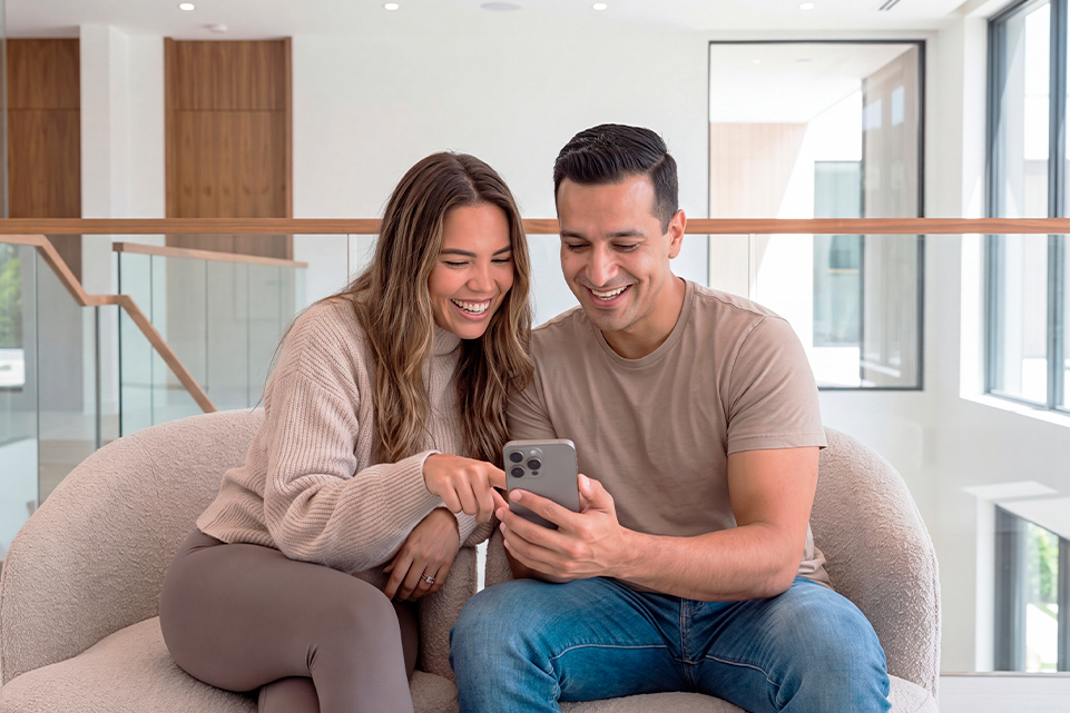Pareja celebrando frente al celular al imaginar ganar el Sorteo Mi Sueño de Sorteos Tec.
