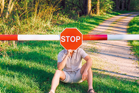 Hombre sentado frente a una barrera con señal de STOP, imagen sobre errores al jugar la lotería.